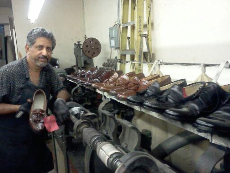 Giovanny at his workbench surrounded by rows of repaired shoes